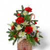 Our ceramic gingerbread house container is bursting with classic red carnations and
