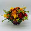 A vibrant fall centerpiece crafted in a deep red bowl, this arrangement