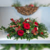 A festive long lasting  centerpiece containing fragrant holiday greens, red roses