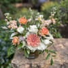 Fluffy white hydrangeas, roses, and stock complimented with peach toned flowers like
