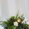 a birch vase with white roses, holiday ornament and winter greens with