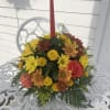 Round centerpiece with a single taper, yellow buttons and solidago, daisies, orange