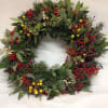 A bright, winter wreath of mixed berries, pine, eucalyptus, and fresh bay