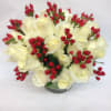 White roses are complimented by rosy red berries in this low vase