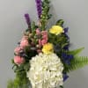 Cylinder vase featuring groupings of roses, hydrangea, snap dragons, carnations and other