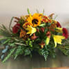 A lovely gathering-table centerpiece approximately 3 feet long of reds, browns, oranges