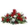 Christmas greens, carnations, and accents of red roses makes this centerpiece a