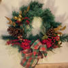 A medium sized fresh or artificial Christmas Wreath with pinecones, ornaments, and