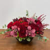 A sensuous, texturally indulgent arrangement of heart roses, pink cymbidium orchid, hypericum