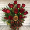 A Dozen Red Roses arranged in a glass vase filled with Christmas