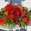 Long and low centerpiece with orange roses, alstroemeria, bronze mums, red daisies