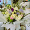 An assortment of purple and white flowers wrapped in premium paper.
Hand Bouquet.

If