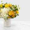 The honeycomb designed vase filled with yellow and white garden flowers. 