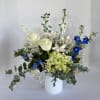 This elegant arrangement of white roses, blue delphinium, green hydrangea, babies breath