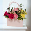 A stylish arrangement designed in a soft blush handbag container, featuring a
