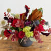 This arrangement is presented in a dark blue cylinder vase. It features