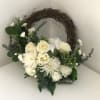 White flowers and rich greens on a grapevine wreath