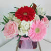 Pink, red and white flowers in a glass cube vase. Make someones