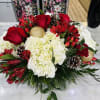 Bustling with fresh Christmas greens, red roses, hypericum berries, hydrangea, pine cones