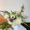 Crisp, clean, and bright, this arrangement features white blooms and holiday greenery