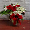 White alstro lilies and red roses with evergreen and red berries.