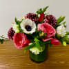 In a clear glass vase combinations of dahlia,  garden roses, tulips