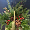 A basket filled with evergreens, pine cones and berries.