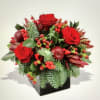 in a glass vase Xmas greenery with a red roses, red tulips