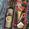 A bottle of wine in a box with dried fruit, cookies, chocolates