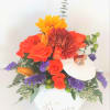 A ceramic container with a lid, filled with fall mixed flowers and
