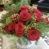 One dozen red roses on a glass cylinder with Christmas Greens 