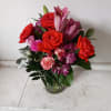 Beautiful orange roses mixed in with pink lilies, purple/pink alstroemeria and light