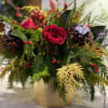 Beautiful arrangement full of winter greens, pine cones, berries, and red roses