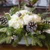 White and green holiday centerpiece in a ceramic container.