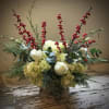 Holiday greens, nestled in white hydrangea with pops of red berries and