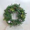 A classic evergreen wreath adorned with natural pinecones, festive berries, and textured