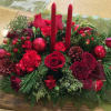 Traditional style centerpiece, with candles, winter greens, roses, ornaments, and red berries.