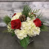 An elegant arrangement of white hydrangea and red roses with festive greens