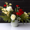 A fun and festive arrangement full of fresh winter greens and red