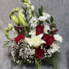 A festive Christmas arrangement featuring snowy pinecones, lush evergreens, red roses, white