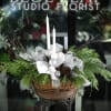 Lush, fragrant evergreens line a festive wooden basket filled with white and