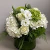 Beautiful white and green arrangement with Winter greens in a glass container