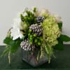 An elegant arrangement with Hydrangea, white Freesia, white Roses, bright Green Hypericum