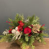 This arrangement showcases a lush sweep of mixed winter greens accented by