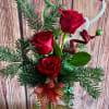 3 Cheery Red roses arranged with Christmas decor and Greens. (All designs
