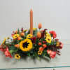 Low centerpiece of fresh flowers with a candle.