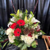 A traditional floral arrangement in red, white and green with Christmas ball