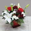 Assorted red and white flowers decorated with cone pines and Christmas greens
