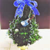 Boxwood Christmas tree decorate with fresh flowers, satin bow, and christmas ornaments.