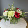 A mix of wintergreens, red roses, and white florals arranged in a